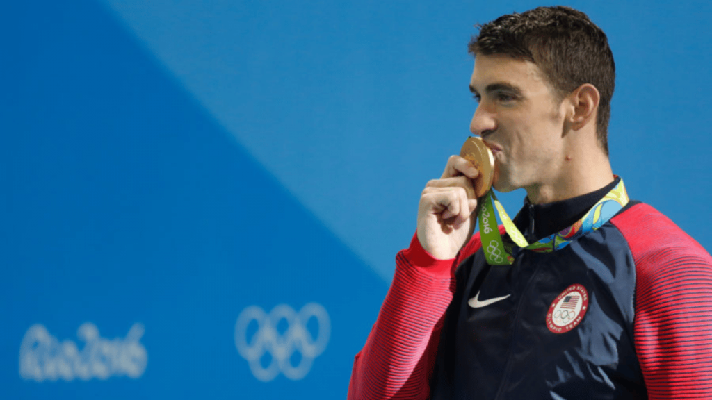 Michael Phelps x Sports Illustrated Drop NFTs For Mental Health A picture of Olympic Icon Michael Phelps clutching his Gold Medal at a previous Olympics game.