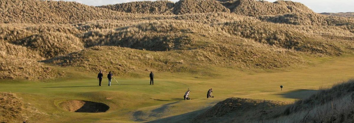 A group of people play gold on the course at Spey Bey Golf Club.