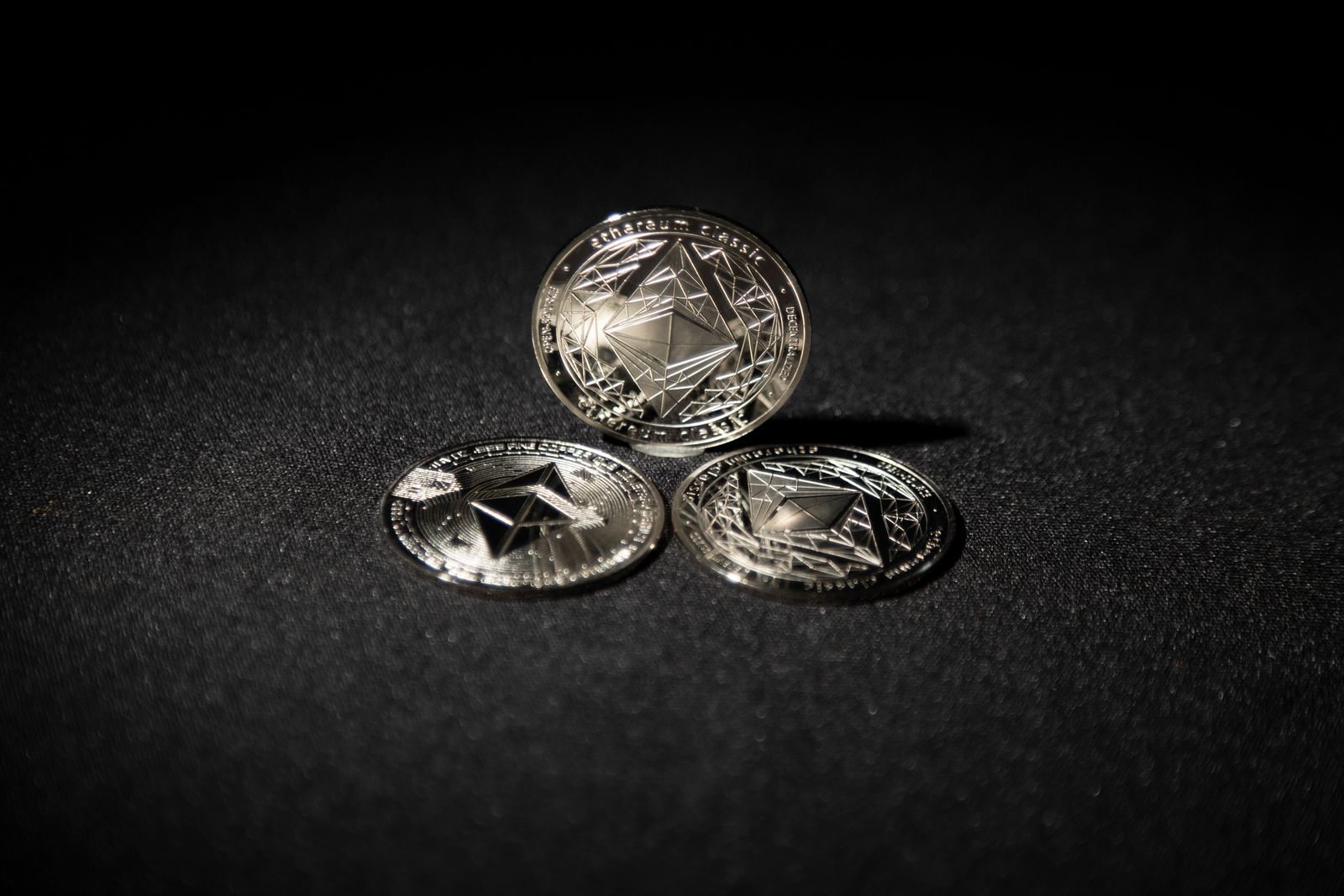 Three silver Ethereum coins on a dark textured surface